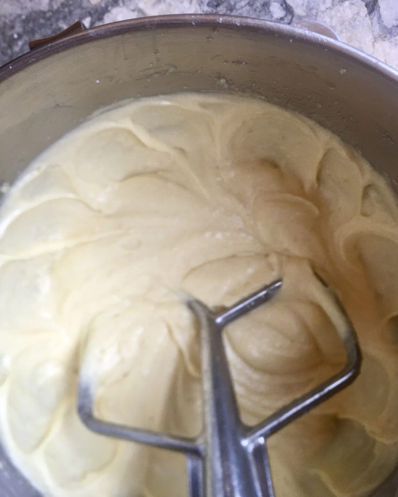 Filling for almond custard pie, beaten to thick flutty goodness using stand mixer, top down looking into metal bowl with paddle attachment submerged in filling