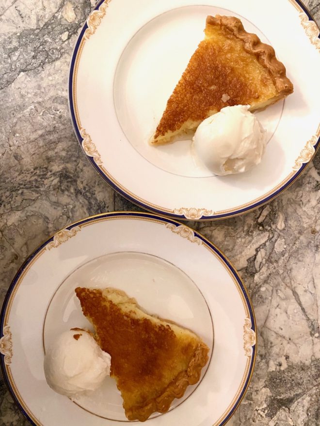 Twin Tyler pie pieces, from above, on elegant china dessert plates, with ice cream, on a marble countertop