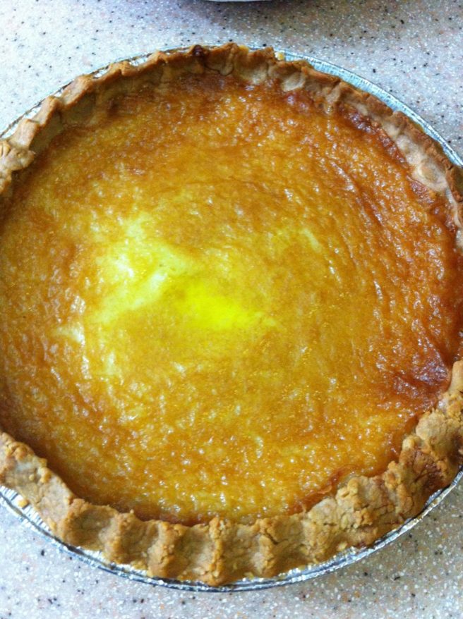 A top down view of a bright yellow custardy lemony Tyler Pie with hand crimped substantial crust on counter top
