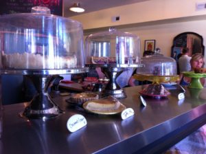 View of baked goods on the counter at WPA Bakery with one piece of Tyler Pie in the center and windows and shop in the background