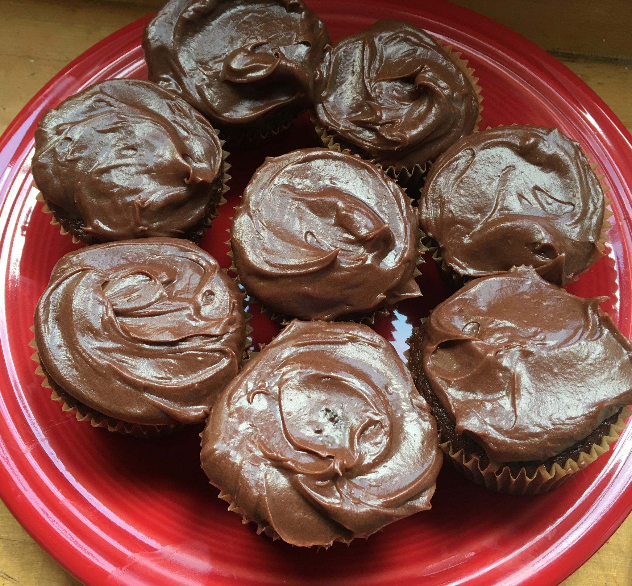 Eight luscious chocolate cupcakes from above, placed on red plate with one in center