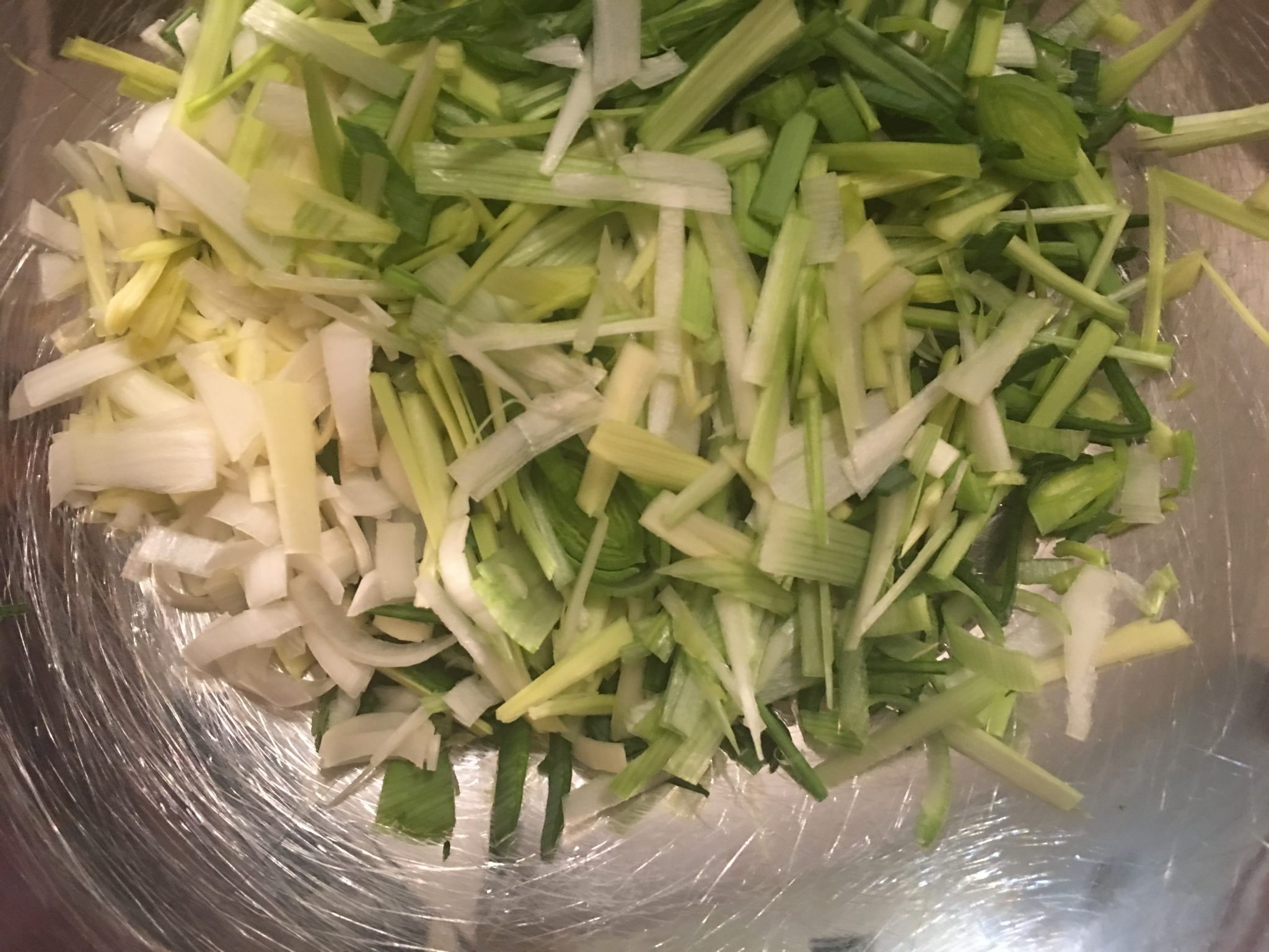 Chopped up leeks, ready to be sauteed with cabbage for this Leeks and Cabbage recipe, looking down into a big stainless steel bowl