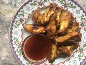 Tasty chicken wings seasoned with mustard and honey and served with a hot-sauce/honey dipping sauce in a small bowl on the side.