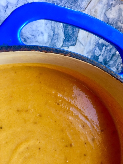 Pumpkin soup top down image in a big blue enamel cast iron pot with marble background