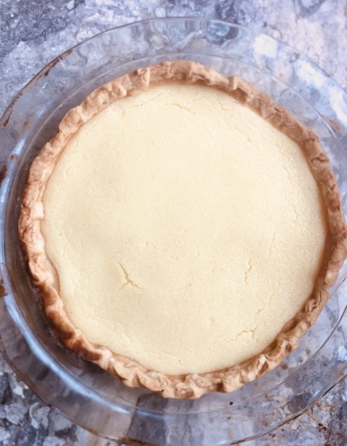 Buttermilk pie in pastry crust, glass pie plate on marble counter