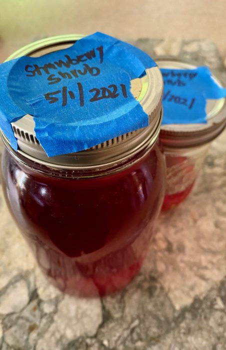 Mason jar of strawberry shrup syrup on marble with blue tape-sharpie label on top